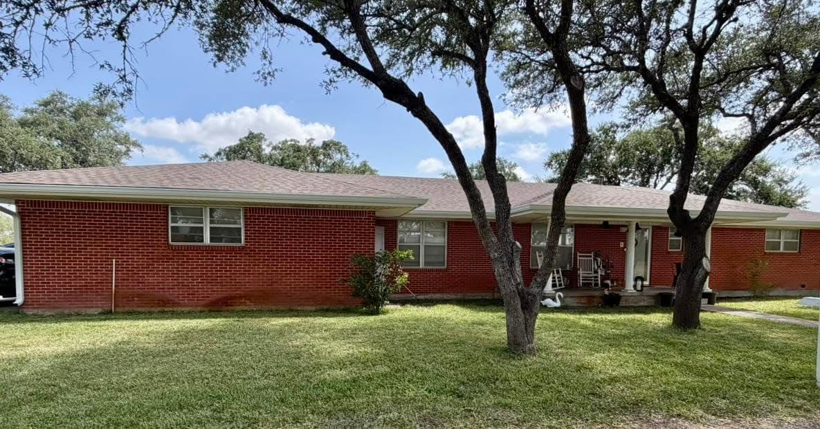 A long unbroken seamless gutter run across the eave of a brick ranch home