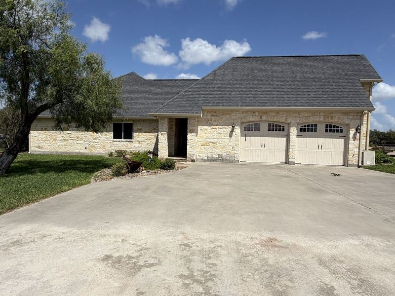 Refugio stone house and garage with seamless gutters along the eave
