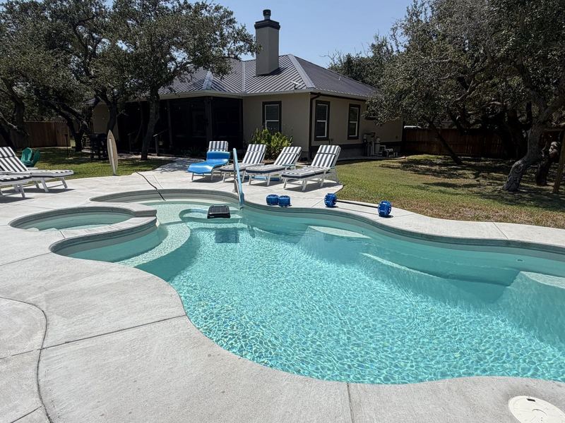 Pool behind a tan ranch with seamless gutters in the Rockport–Aransas area